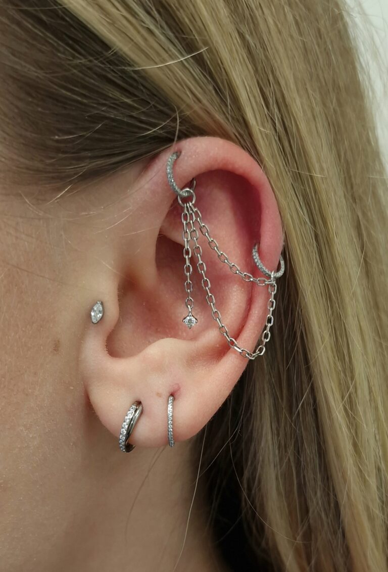 An ear with chain-connected earrings